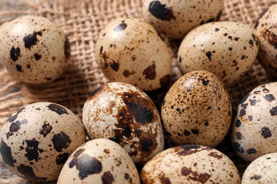 Fresh quail eggs on burlap fabric, closeup
