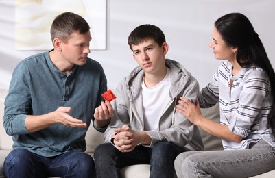 Parents talking with their teenage son about contraception at home. Sex education concept