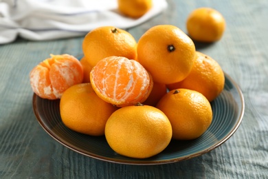 Photo of Fresh tangerines on blue wooden table. Citrus fruit