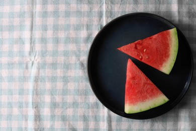 Sliced fresh juicy watermelon on checkered light blue tablecloth, top view. Space for text