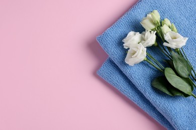 Soft folded blue towel with flowers on pink background, top view. Space for text