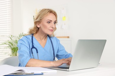 Photo of Doctor working on laptop at table in clinic. Online medicine concept