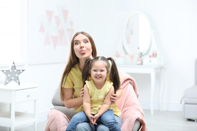 Young mother with little daughter having fun at home