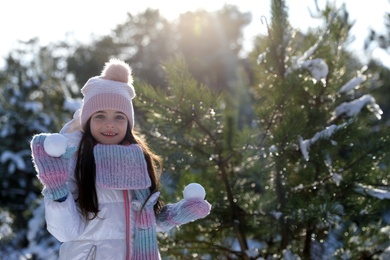 Cute little girl with snowballs in winter forest