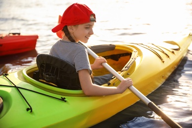 Happy little girl kayaking on river. Summer camp activity