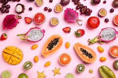 Many different delicious exotic fruits on pink background, flat lay