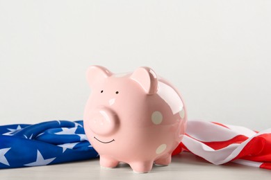 Piggy bank and American flag on white wooden table
