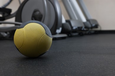 Yellow medicine ball on floor in gym, space for text