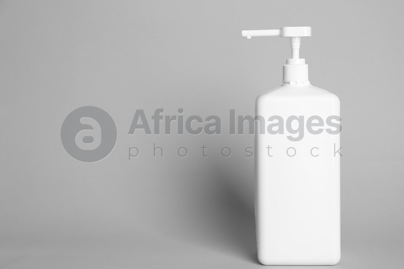 Dispenser bottle with antiseptic gel on light grey background. Space for text