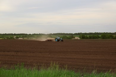 Tractor plowing agricultural field under cloudy sky