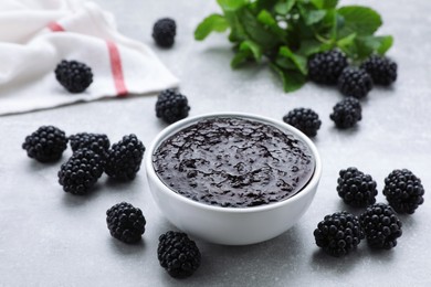 Photo of Blackberry puree in bowl and fresh berries on light grey table