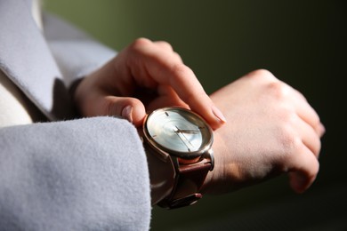 Woman with luxury wristwatch on dark background, closeup