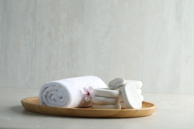 Photo of Spa stones, towel and fresia flower on light table. Space for text