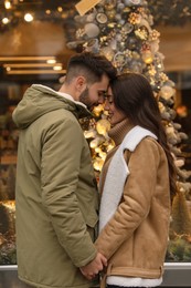 Lovely couple near store decorated for Christmas outdoors