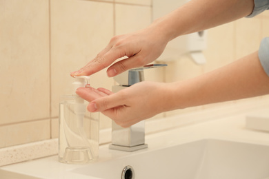 Woman applying antiseptic soap onto hand in bathroom, closeup. Virus prevention
