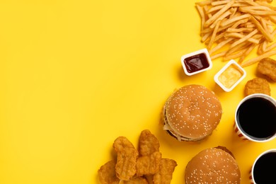 Photo of Different fast food on yellow background, flat lay. Space for text