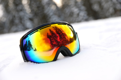 Stylish ski goggles on snow outdoors. Winter sport equipment