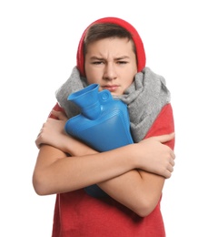 Sick teenage boy with hot water bottle on white background