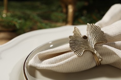 White fabric napkin with beautiful decorative ring for table setting on plate, closeup