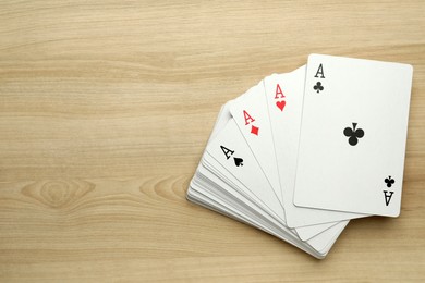 Four aces playing cards on wooden table, flat lay. Space for text