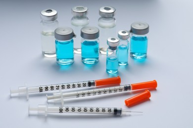 Disposable syringes with needles and vials on white background