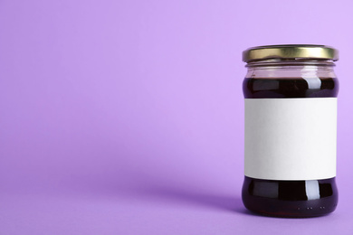 Jar of organic honey with blank label on violet background. Space for text