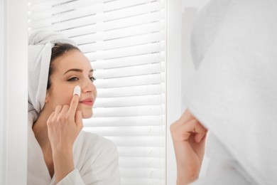 Photo of Woman using silkworm cocoon in skin care routine near mirror at home