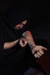 Addicted man taking drugs on dark background