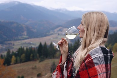 Photo of Young woman drinking wine in peaceful mountains