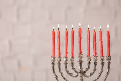 Silver menorah with burning candles on light background, space for text. Hanukkah celebration