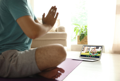 Distance yoga course during coronavirus pandemic. Man having online practice with instructor via laptop at home, closeup