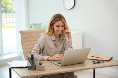 Pretty young woman working with laptop in office