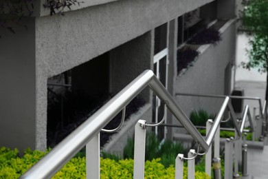 Photo of Outdoor staircase with metal handrails near beautiful plants, closeup