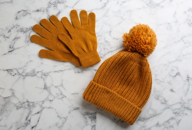 Stylish gloves and hat on white marble background, flat lay