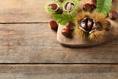 Fresh sweet edible chestnuts on wooden table, above view. Space for text