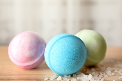 Photo of Colorful bath bombs and cosmetic salt on wooden table