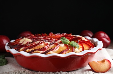 Delicious cake with plums in baking dish, closeup