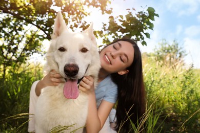 Photo of Teenage girl hugging her white Swiss Shepherd dog in park