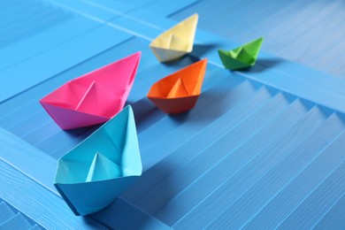 Colorful paper ships on blue wooden background