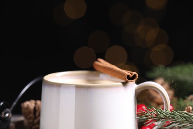 Photo of Tasty eggnog with cinnamon stick against blurred lights, closeup