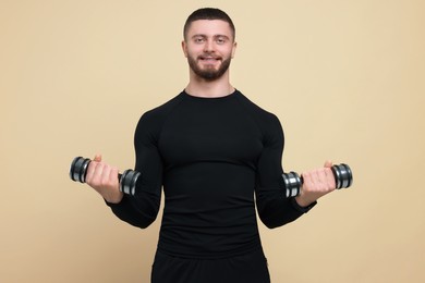 Photo of Handsome sportsman exercising with dumbbells on brown background