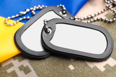 Military ID tags and Ukrainian flag on pixel camouflage, closeup