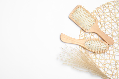 Wooden hair brushes and spikelets on white background, top view