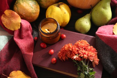 Photo of Beautiful autumn composition with orange chrysanthemum flowers and burning scented candle on wooden table, above view