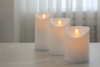 Glowing decorative LED candles on grey table. Space for text