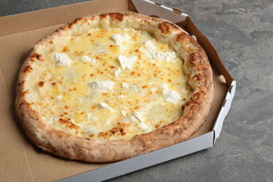Delicious hot cheese pizza in takeout box on grey table