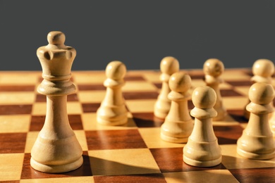 Queen and pawns on wooden chess board, closeup. Social roles concept