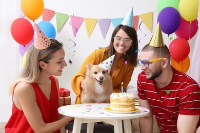 Happy friends celebrating their pet's birthday in decorated room