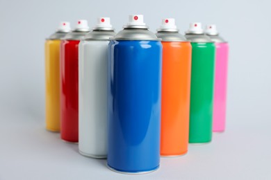 Colorful cans of spray paints on light grey background