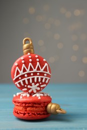Beautifully decorated Christmas macarons on light blue wooden table against blurred festive lights